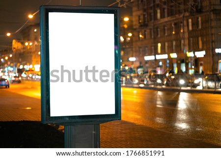 Advertising vertical billboard in the city glows at night. MOCKUP for design