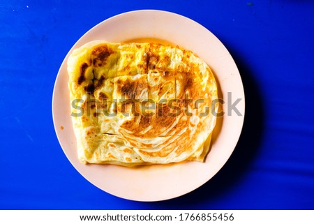 Flatlay picture of "roti telur"on table during breakfast. A flatbread mix with egg.