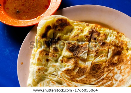 Flatlay picture of "roti telur" with dhal on table during breakfast. A flatbread mix with egg.
