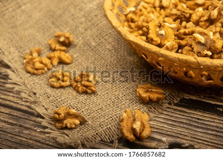 Peeled walnuts in a wicker basket and peeled walnuts scattered on a wooden table covered with rough-textured burlap. Healthy diet. Fitness diet. Close up.