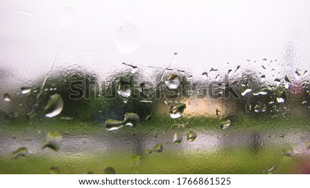 Drops on glass overlooking the street. Car window and the road behind it. Urban theme stock photo for design