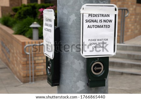 "Pedestrian signal is now automated. Please wait for signal before crossing" sign at a crosswalk