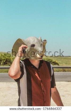 Conceptual image of a young elephant-headed human making a work call with his mobile phone