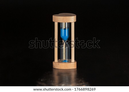 blue sand hourglass on black background