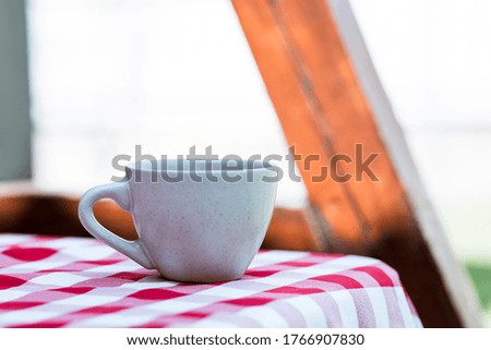 cup on the background of a checkered tablecloth on the street, coffee on a picnic