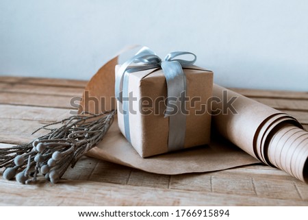 gift with a silver bow on a wooden table with craft paper and a flower