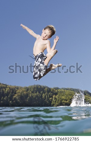 Young boy jumping over lake