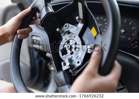 Close Up car steering wheel repair after the accident. Disconnecting of driver's airbag. With soft-focus.  Royalty-Free Stock Photo #1766926232