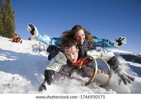 Couple riding on sled, Luesener Alm, Dolomite Alps, South Tyrol, Italy