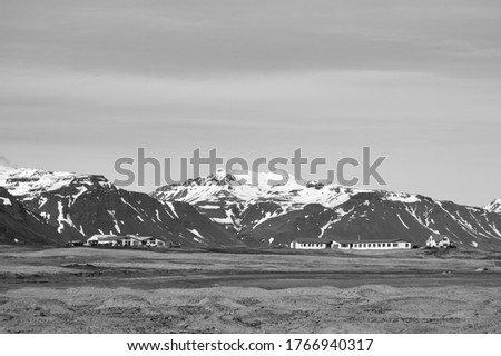 Isolated houses on top of a hill and snowy mountain chain as backgroung in black and white