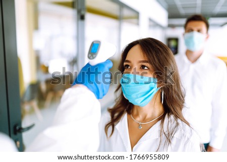 Visitors must go through fever measures using infrared digital thermometer check temperature measurement on the forehead. Covid-19, quarantine or virus outbreak concept. Royalty-Free Stock Photo #1766955809