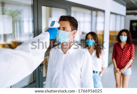 Visitors must go through fever measures using infrared digital thermometer check temperature measurement on the forehead. Covid-19, quarantine or virus outbreak concept. Royalty-Free Stock Photo #1766956025