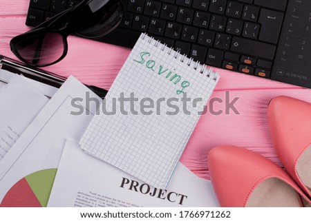 Close up of black keyboard, sun glasses, notepad on pink background.