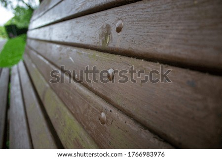Old wooden brown bench close-up. In the background a blurred green park. Concept.