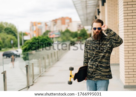 Young man walking with longboard on the street