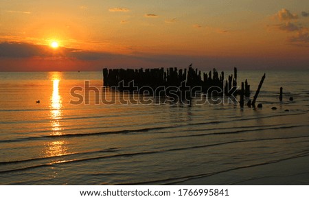 sunrise on the beach with a view of an old sea pier