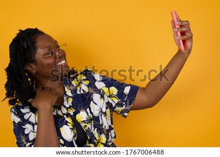 Portrait of a pretty happy African American girl taking a selfie isolated over bright background