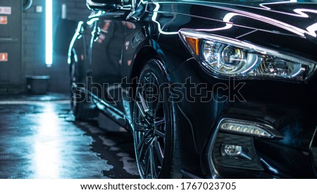 Close up of headlight detail of modern luxury sportscar with reflection on red paint after wash & wax. Front view of supercar with brick wall. Concept of car detailing and paint protection background. Royalty-Free Stock Photo #1767023705