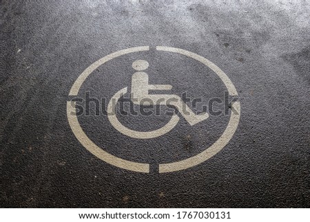 Parking lot with painted sign of wheelchair. Parking spaces for disabled customers.