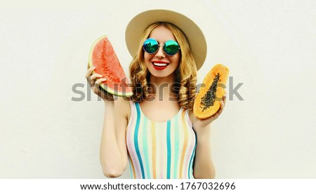Happy woman with fruits slice of watermelon and papaya wearing straw hat, sunglasses on white background