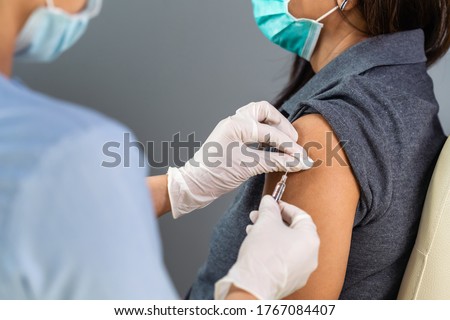 close up doctor holding syringe and using cotton before make injection to patient in medical mask. Covid-19 or coronavirus vaccine Royalty-Free Stock Photo #1767084407