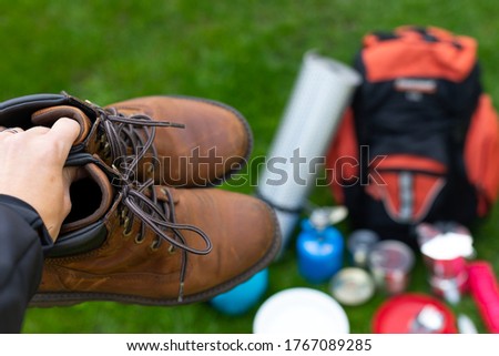 Picture of camping tools on the grass - backpack, tent, gas tank, cans, compass, etc - ready to go in the woods