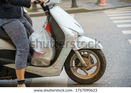 Side view of a woman on a motorcycle scooter stop at crosswalk