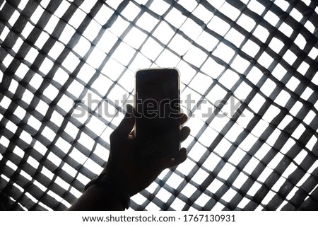 A silhouette shot of mobile in hand and light through the ocatbox grid.