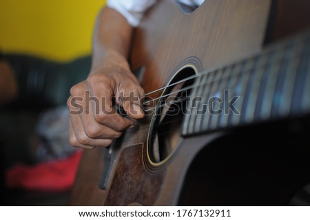Man's hands play with an acoustic guitar. Close-up display. Selective focus.