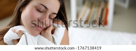 Girl sitting on white bed with closed eyes resting. Relaxation comfortable pleasant bed in your home. Improve sleep quality feel fresh, alert and full energy. Rest during self-isolation in apartment Royalty-Free Stock Photo #1767138419