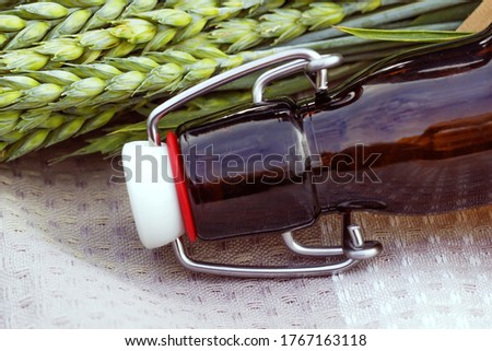 Close-up of the neck of a dark-colored glass beer bottle with a bugle stopper and wheat in the open air.Brewing.International beer day.The concept of giving up alcohol
