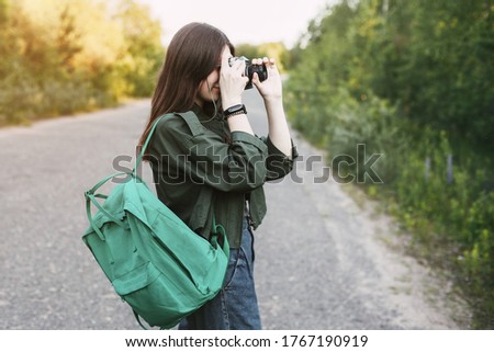 Cute brunette looks at the camera lens. A girl photographs nature. Side view, space for text
