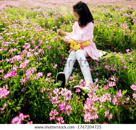 Asian little girl sitting and playing in the grass