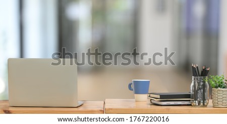 Behind of computer laptop is putting on a wooden working desk surrounded by office accessories. Royalty-Free Stock Photo #1767220016