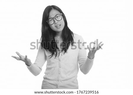 Portrait of stressed young Asian nerd woman looking angry with arms raised