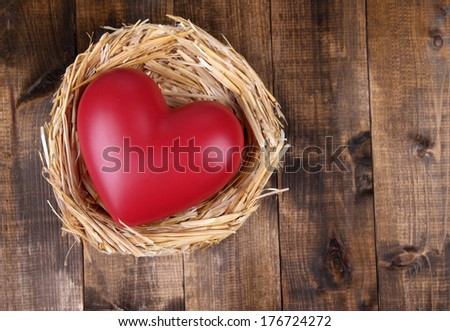 Decorative heart in nest, on wooden background