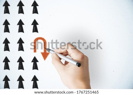 Hand drawing red rotates arrow on concrete wall. Leadership and creativity concept. Close up