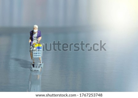 A woman doing safe solo shopping at supermarket wearing a face mask. Miniature people figurines toys conceptual photography.