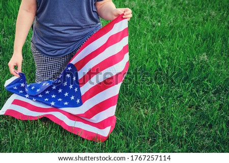 A woman knelt with a US flag, background green grass in the park