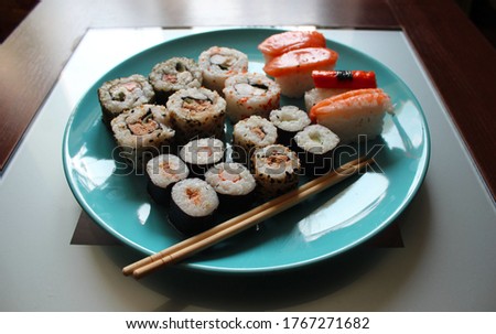Sushi meal and sticks on a blue plate on the table. 