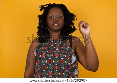 Young beautiful afro american woman wearing glasses over  yellow background  pointing up with fingers number ten in Chinese sign language Shi