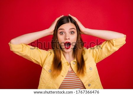 Photo portrait of funny amazed shocked young lady with opened mouth holding hands on head isolated bright color red background
