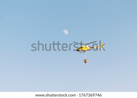 Helicopter flying with sky and moon background. Firefighter concept and extinguishing fires and wildfires.