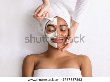 Black woman having white clay mask on half of her face, top view Royalty-Free Stock Photo #1767387863