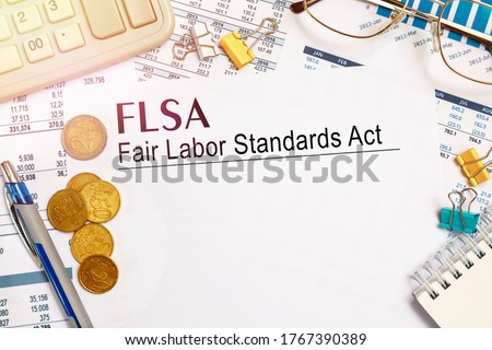 Desktop office desk, notebook, glasses, pen and documents with FLSA Fair Labor Standards Act on a tabl