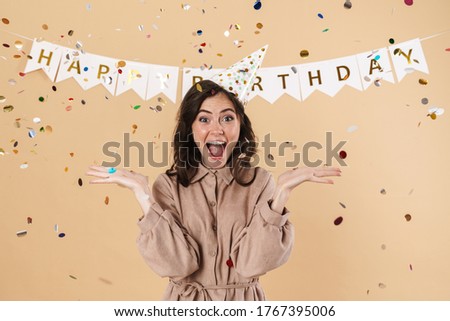 Image of excited cute woman in party cone expressing surprise on camera isolated over beige background