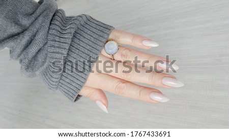 beautiful woman hands with long nails light white manicure and a bottle of nail polish