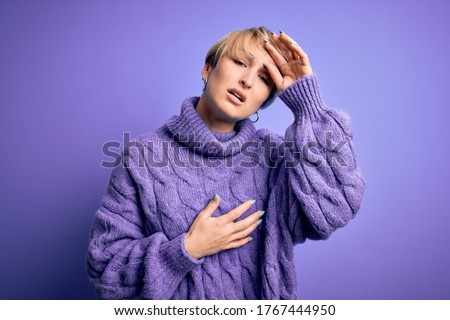 Young blonde woman with short hair wearing winter turtleneck sweater over purple background Touching forehead for illness and fever, flu and cold, virus sick