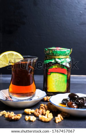 Azerbaijani black tea in a glass of armudu, walnut jam, and walnuts on the table. Azerbaijani, Turkish, Oriental cuisine, tea traditions
