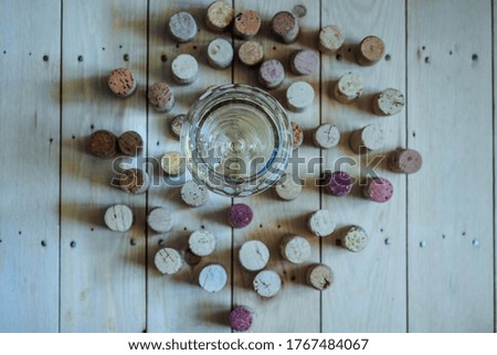White glass of bubbles wine, cork around the glass on a wooden background